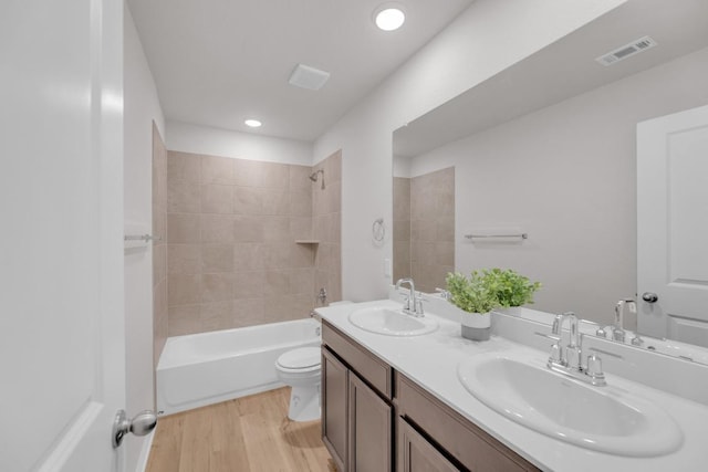 bathroom with toilet, wood finished floors, a sink, and visible vents