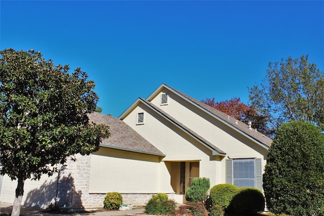 view of front of house with a garage, roof with shingles, and stucco siding