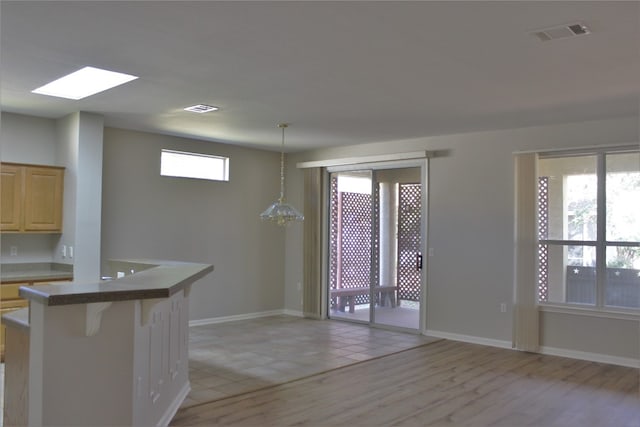 kitchen featuring light brown cabinetry, light wood finished floors, a breakfast bar, and visible vents