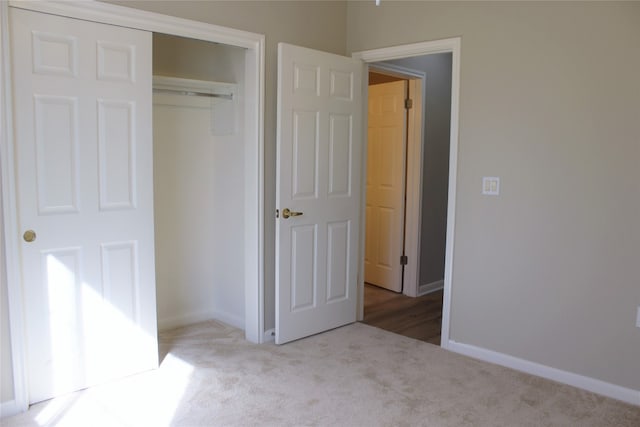 unfurnished bedroom with carpet, a closet, and baseboards