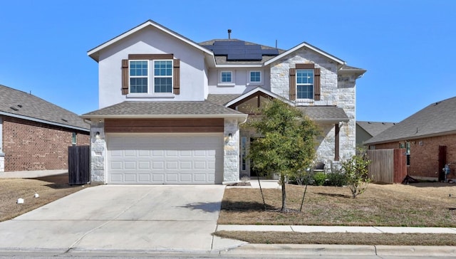 traditional-style home with an attached garage, stone siding, solar panels, and concrete driveway