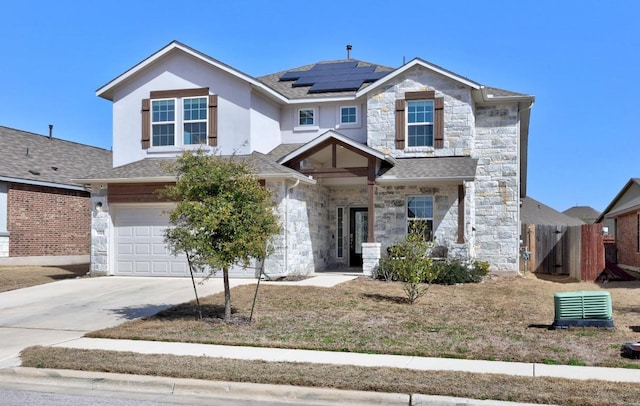 view of front of home with solar panels, concrete driveway, an attached garage, fence, and stone siding