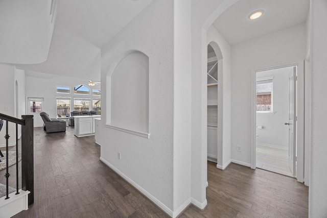 hallway with a healthy amount of sunlight, stairs, baseboards, and dark wood finished floors