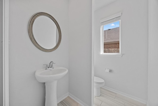 half bathroom with baseboards and toilet