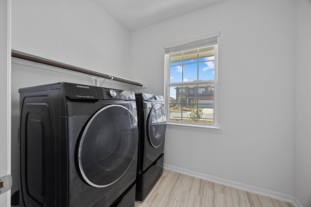 clothes washing area featuring washing machine and dryer, laundry area, and baseboards