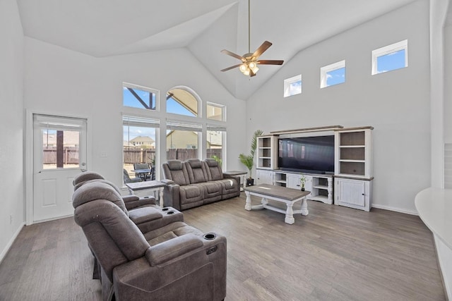 living area with high vaulted ceiling, plenty of natural light, wood finished floors, and a ceiling fan