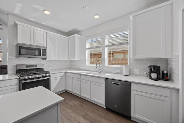 kitchen featuring backsplash, appliances with stainless steel finishes, dark wood-style flooring, and a sink