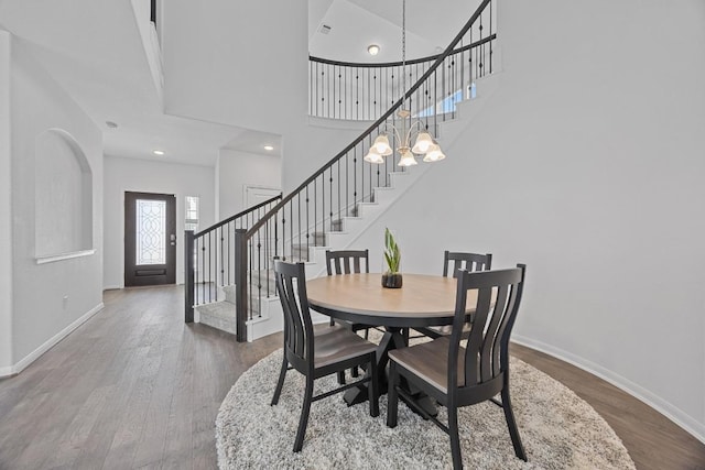 dining room featuring an inviting chandelier, baseboards, stairway, and wood finished floors