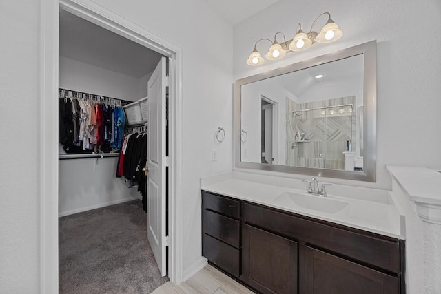 full bath with a stall shower, baseboards, a spacious closet, and vanity