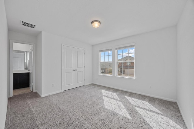 unfurnished bedroom with a closet, carpet, visible vents, and baseboards