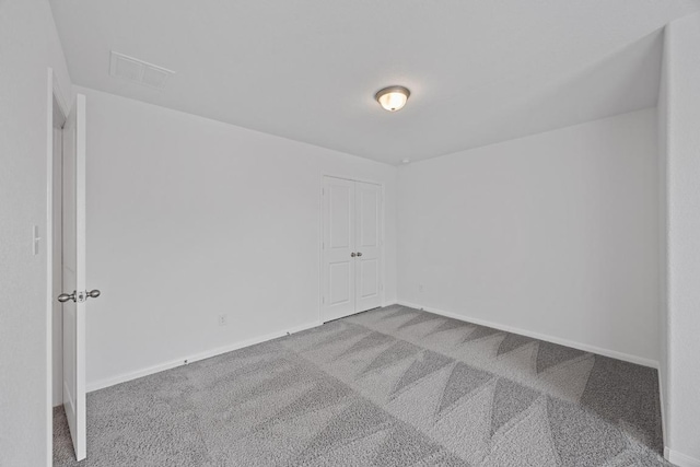 spare room with carpet flooring, visible vents, and baseboards