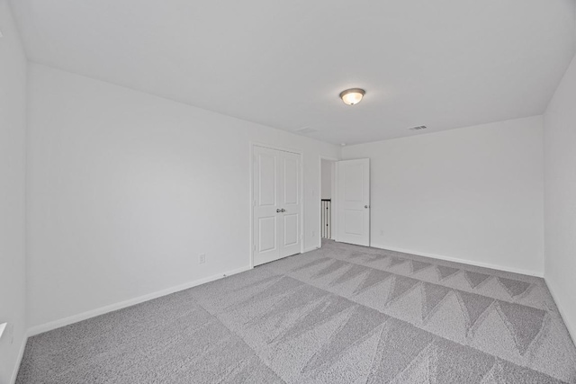 carpeted spare room with baseboards and visible vents