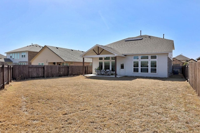 back of property featuring a patio area, a fenced backyard, roof with shingles, and a yard