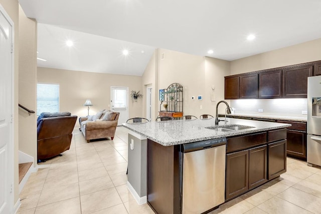 kitchen with an island with sink, a sink, appliances with stainless steel finishes, light stone countertops, and dark brown cabinets