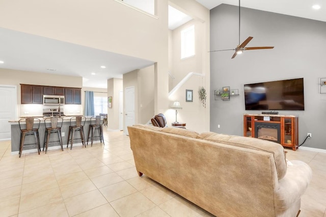 living room with a glass covered fireplace, recessed lighting, light tile patterned floors, baseboards, and ceiling fan