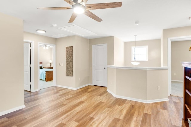 unfurnished room featuring ceiling fan, baseboards, attic access, and light wood-style flooring