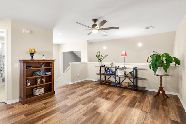 interior space featuring an upstairs landing, visible vents, baseboards, and wood finished floors