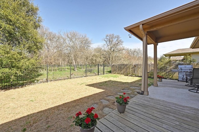 wooden terrace featuring grilling area, a patio, and a fenced backyard