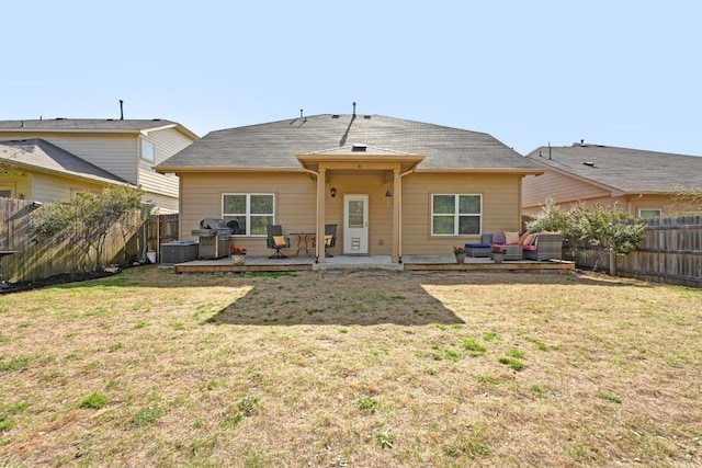 rear view of property featuring a wooden deck, central air condition unit, a lawn, and a fenced backyard