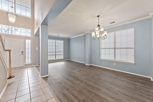 foyer entrance with crown molding, wood finished floors, visible vents, stairway, and an inviting chandelier