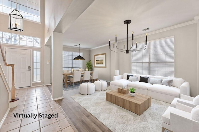 living area with visible vents, ornamental molding, wood finished floors, stairs, and a chandelier