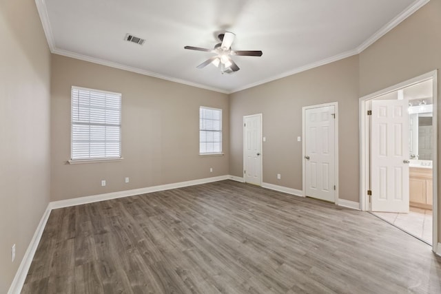 unfurnished bedroom featuring baseboards, visible vents, ornamental molding, wood finished floors, and ensuite bathroom