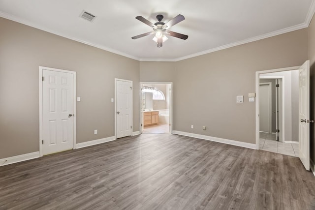 unfurnished bedroom featuring baseboards, crown molding, visible vents, and wood finished floors