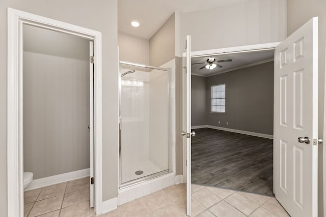 bathroom with toilet, a shower stall, a ceiling fan, and tile patterned flooring