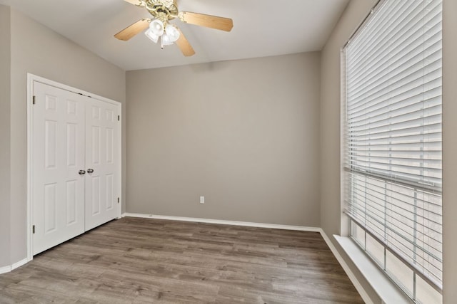 unfurnished bedroom featuring a closet, ceiling fan, baseboards, and wood finished floors