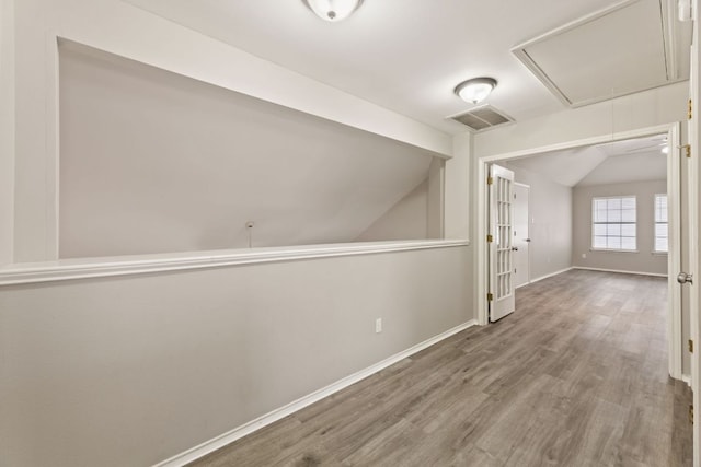 bonus room with wood finished floors, visible vents, baseboards, vaulted ceiling, and attic access