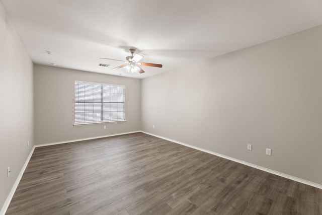 empty room with baseboards, visible vents, ceiling fan, and dark wood-style flooring