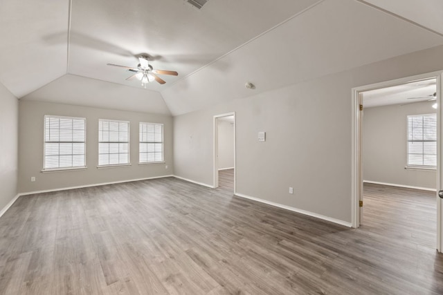 unfurnished living room with a ceiling fan, vaulted ceiling, baseboards, and wood finished floors