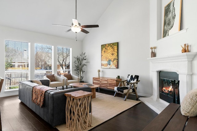 living area with baseboards, high vaulted ceiling, dark wood finished floors, ceiling fan, and a glass covered fireplace