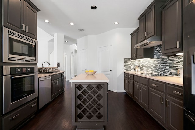 kitchen featuring visible vents, dark wood finished floors, a sink, stainless steel appliances, and under cabinet range hood