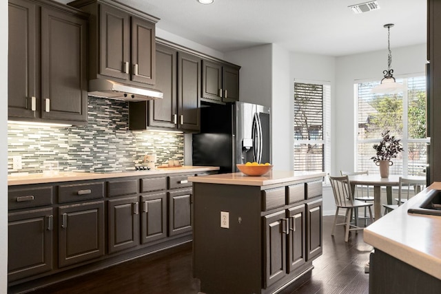 kitchen with visible vents, stainless steel refrigerator with ice dispenser, under cabinet range hood, backsplash, and light countertops