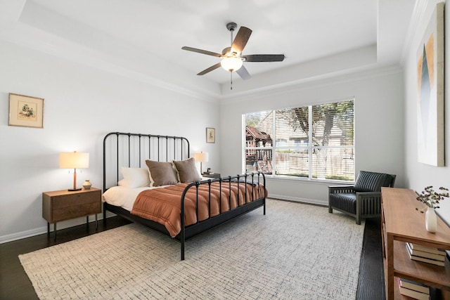 bedroom with ceiling fan, a raised ceiling, and baseboards