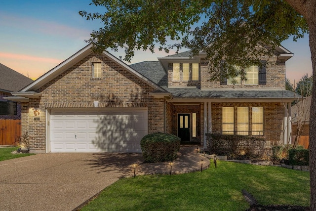 traditional home featuring a garage, brick siding, driveway, roof with shingles, and a front yard