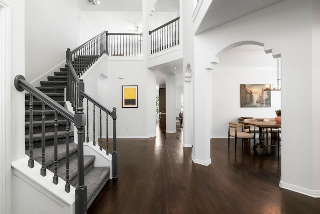 foyer featuring a high ceiling, wood finished floors, baseboards, and arched walkways