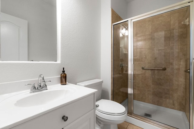 bathroom featuring toilet, a stall shower, vanity, and a textured wall