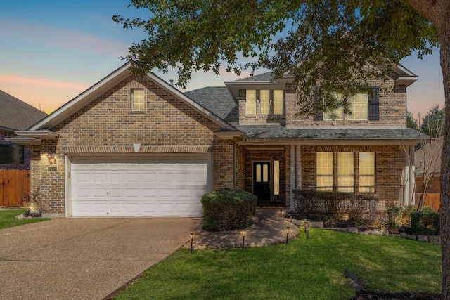 traditional-style home featuring a front lawn, roof with shingles, concrete driveway, a garage, and brick siding