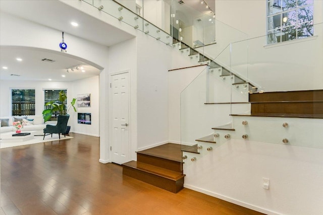 5908 Taylor Draper Cv, Austin, TX 78759 - stairway featuring arched walkways, wood finished floors, recessed lighting, and a towering ceiling