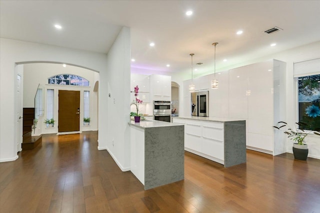 5908 Taylor Draper Cv, Austin, TX 78759 - kitchen featuring modern cabinets, arched walkways, white cabinetry, stainless steel appliances, and dark wood finished floors