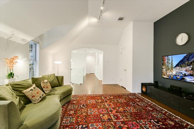 5908 Taylor Draper Cv, Austin, TX 78759 - living room featuring rail lighting, wood finished floors, vaulted ceiling, and arched walkways