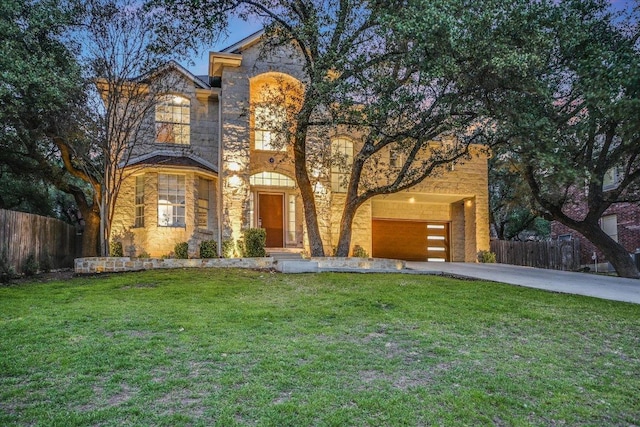 view of front facade featuring a front yard, fence, driveway, a garage, and stone siding