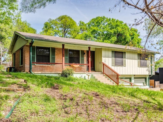 ranch-style home with a garage, covered porch, board and batten siding, and brick siding