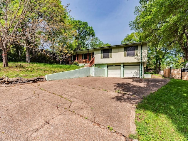 view of front of property featuring a garage, a front yard, concrete driveway, and fence