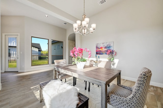 dining space featuring arched walkways, visible vents, an inviting chandelier, light wood-style floors, and baseboards