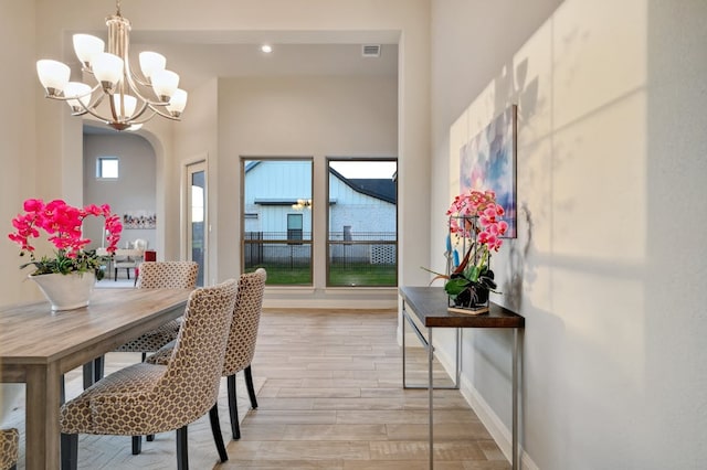 dining space with light wood finished floors, baseboards, visible vents, and arched walkways