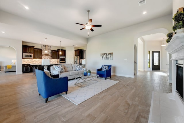 living room featuring arched walkways, ceiling fan, recessed lighting, visible vents, and light wood finished floors