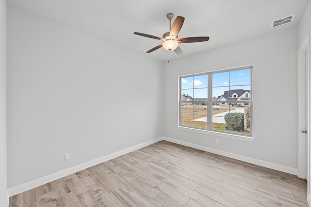 unfurnished room with a ceiling fan, light wood-type flooring, visible vents, and baseboards